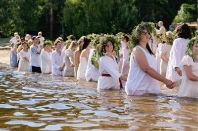 Участники в белом стоят кругом в воде